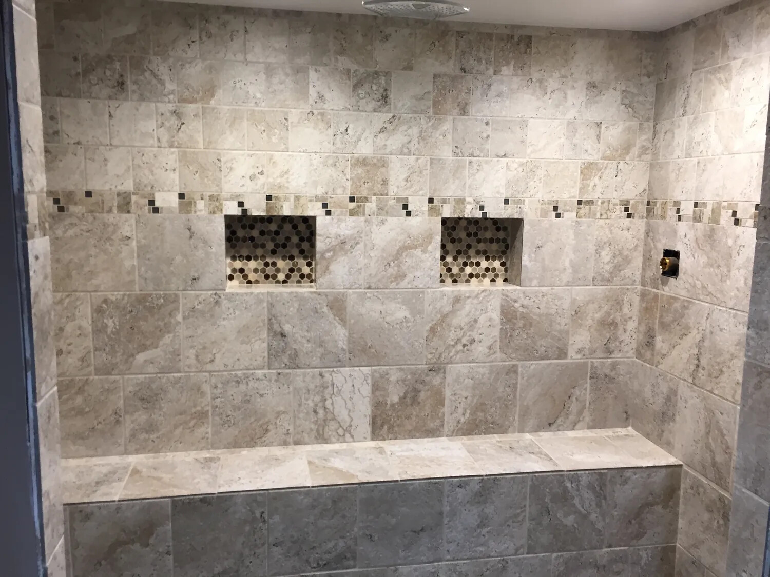 Detailed custom tiled shower with a built-in bench and dual niches